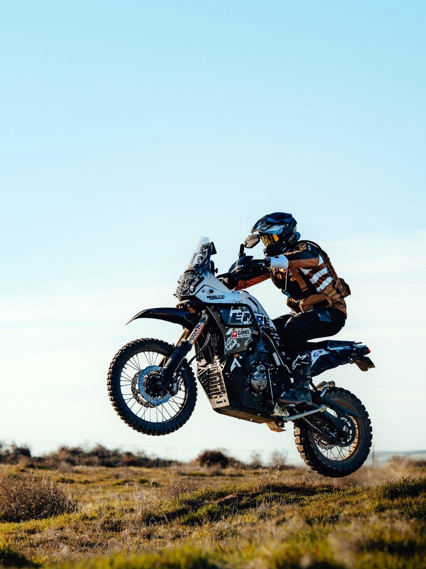 The Ténéré 700 airborne in scrubland against blue sky