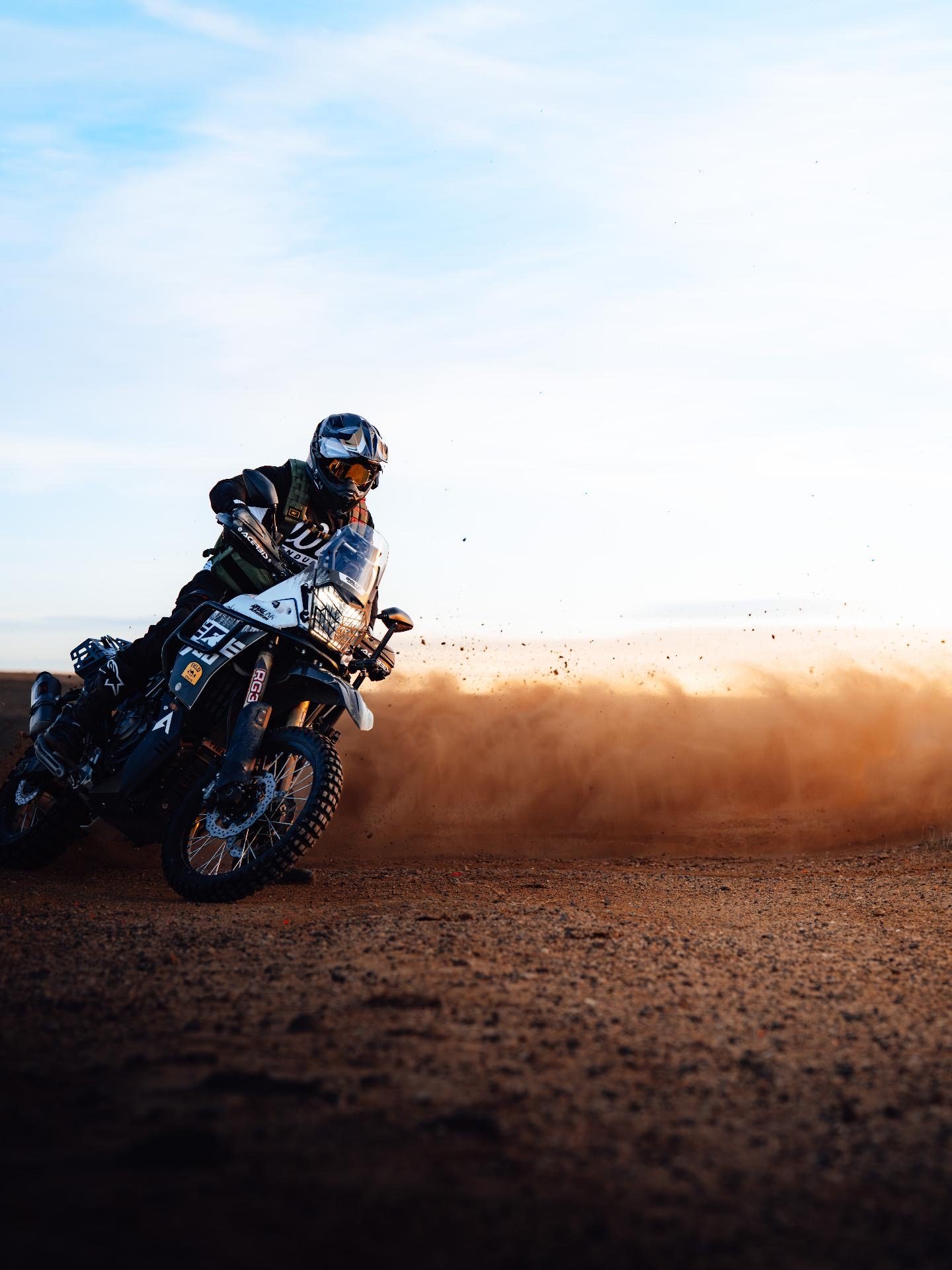 The Ténéré cornering through a rooster tail of dust at sunset